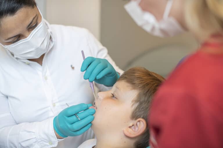 Zahnärztin kontrolliert Zähne beim Jungen