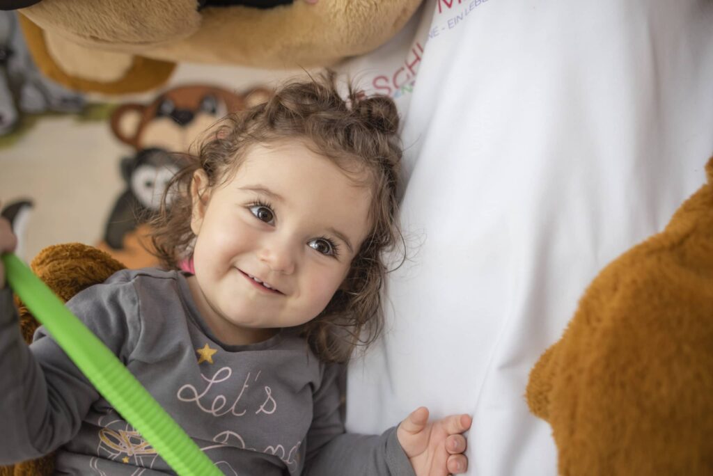 Kind kuschelt sich an Tommy den Bären