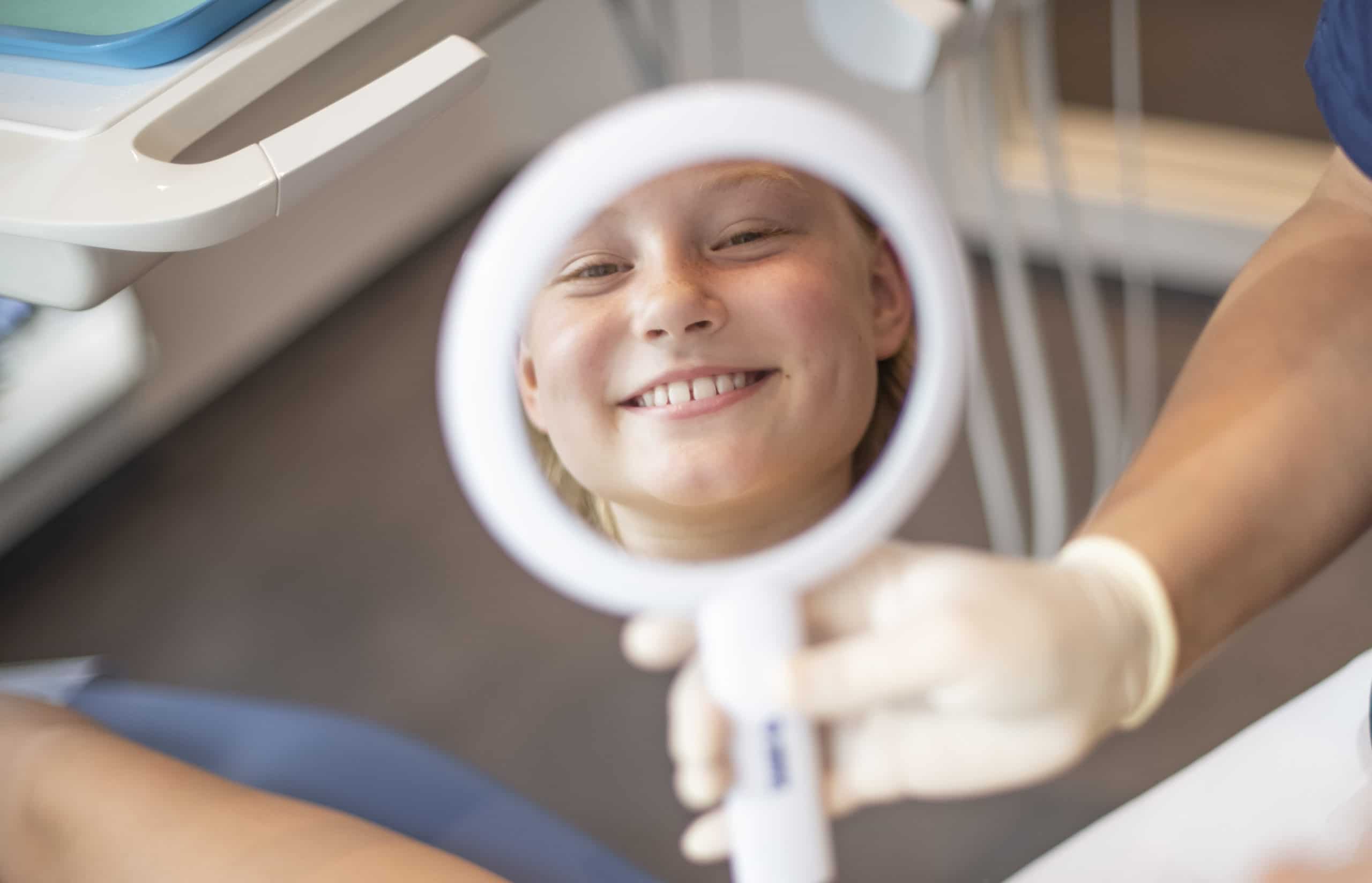 Kleine Patientin lacht in den Spiegel nach ihrer Behandlung