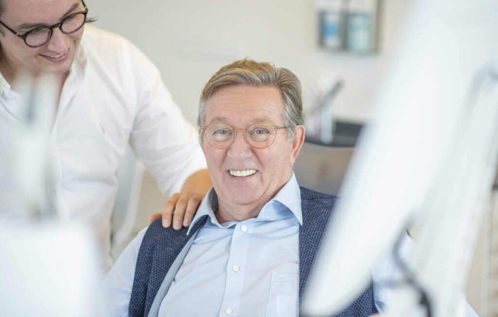 Luca Schlotmann fasst Patient Willi Kuhlmann vertrauensvoll auf die Schulter nach Behandlung
