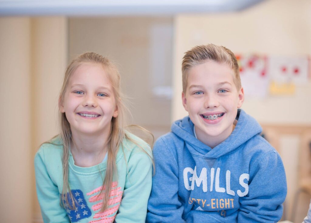 zwei unserer jungen Patienten der kieferorthopädischen Behandlung lächeln in die Kamera